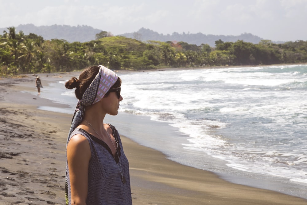 Mujer en camiseta sin mangas de lunares en blanco y negro de pie en la playa durante el día