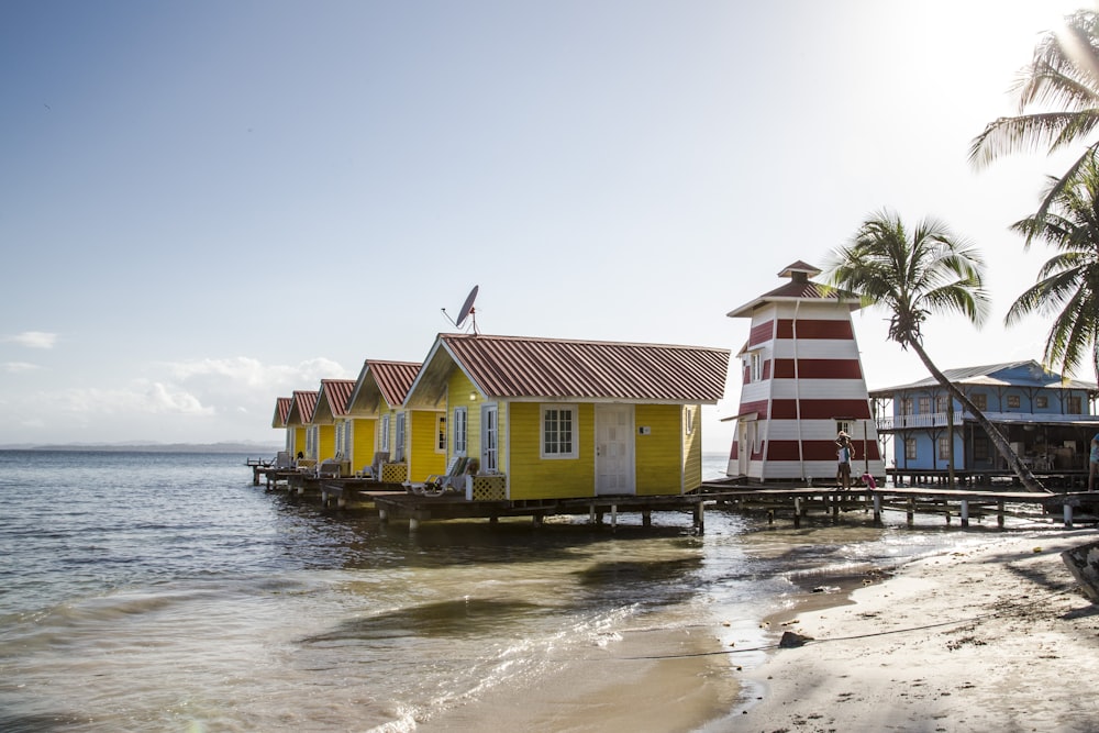 white and red wooden house near body of water during daytime