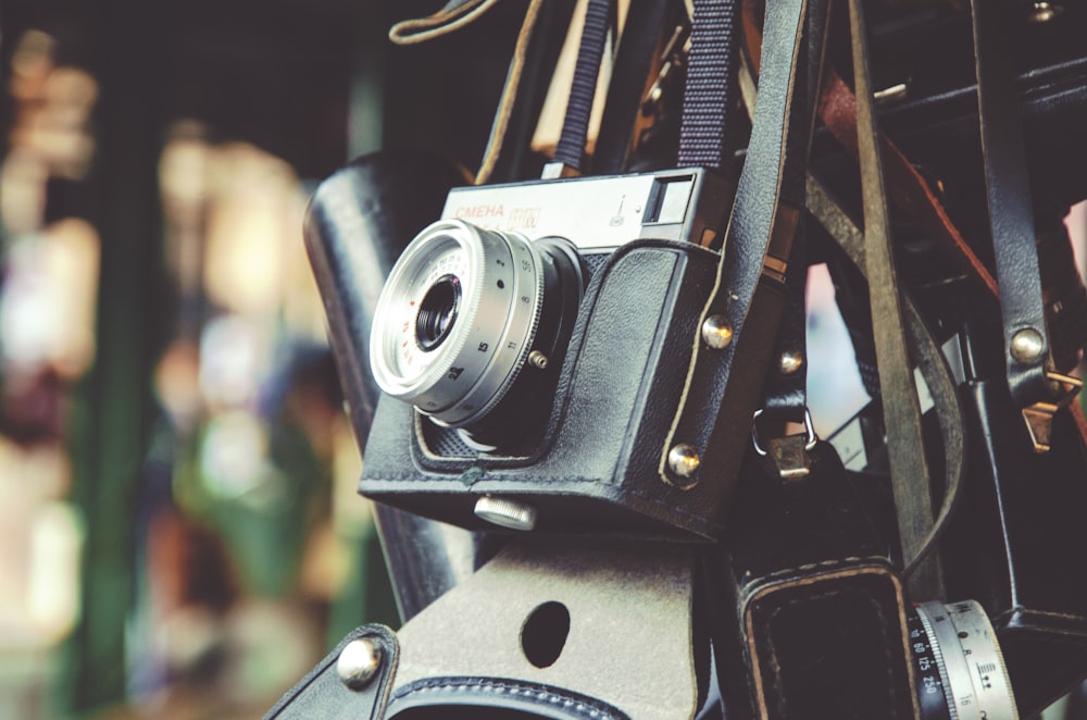 gray and black digital camera and black leather bag