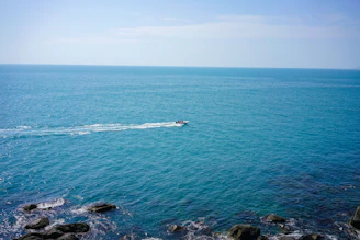 Powerful outboard motor mounted on a fishing boat cutting through calm coastal waters under a clear sky.