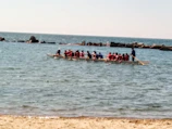 Children learning dragon boat techniques on calm waters with coaches.