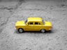 yellow sedan die-cast on gravel