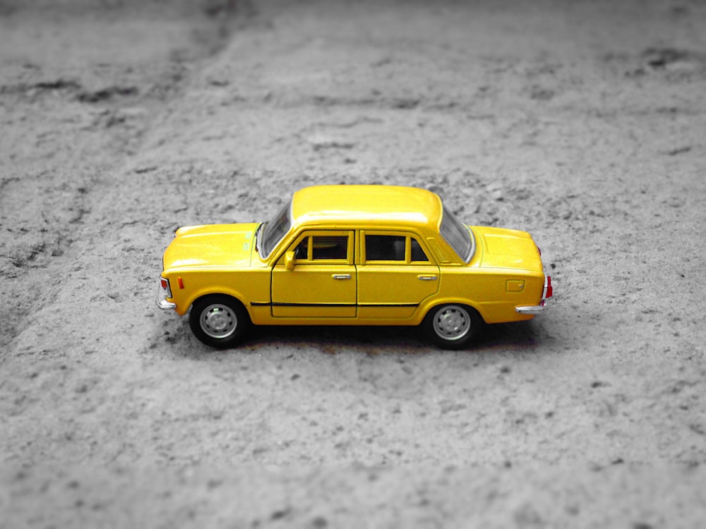 sedã amarelo die-cast sobre cascalho