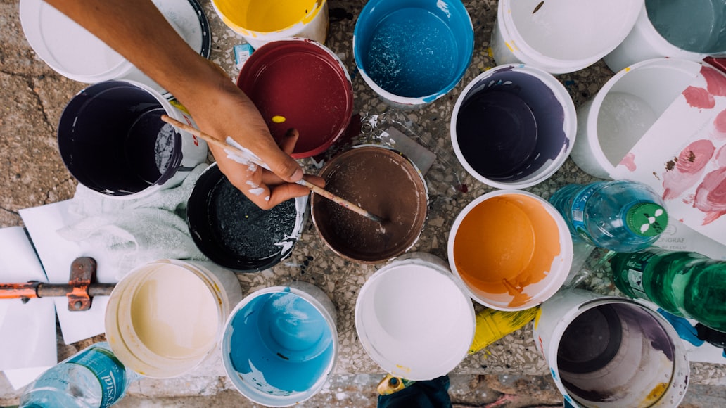 A bucket of paint in different color that choose by painter while they holding a paint brush.