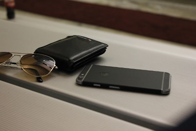A stylish pair of sunglasses placed beside a sleek leather wallet on a marble surface.