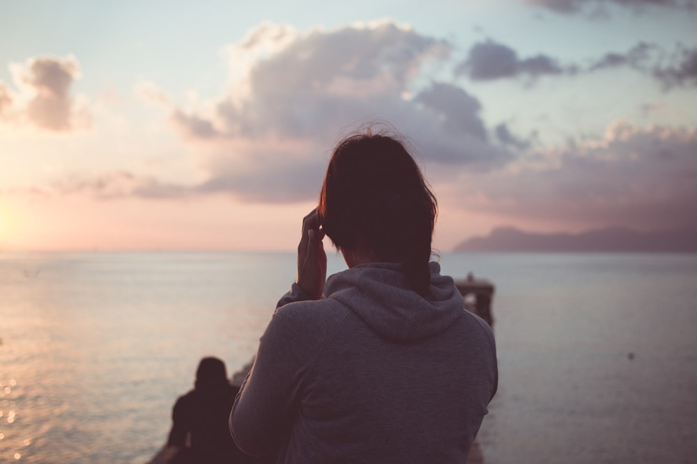 woman in gray hoodie standing at dock