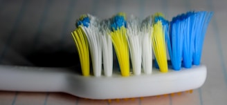 Close-up of a toothbrush with toothpaste being applied, set against a clean white background.