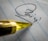 A close-up view of a pen tip positioned on a piece of lined paper with a signature partially visible. The pen's golden color contrasts with the paper's blue lines.