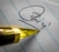 A close-up view of a pen tip positioned on a piece of lined paper with a signature partially visible. The pen's golden color contrasts with the paper's blue lines.