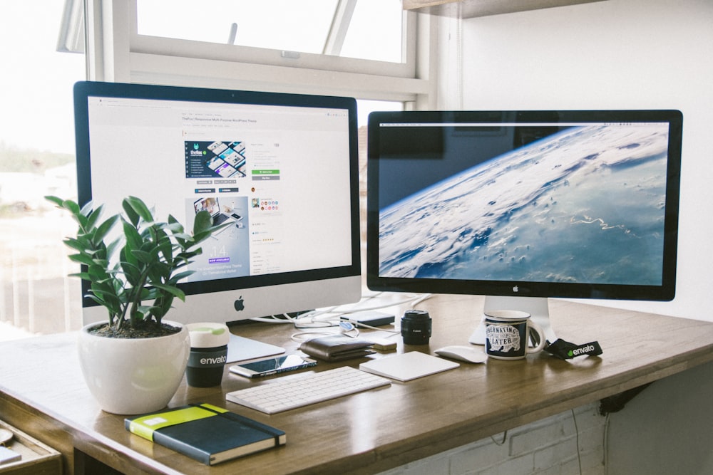 Ein Dual-Monitor-Setup auf einem braunen Schreibtisch.