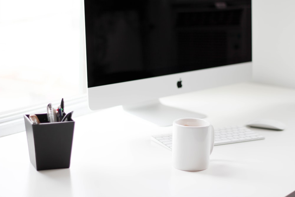 A white Apple computer on a white desk.