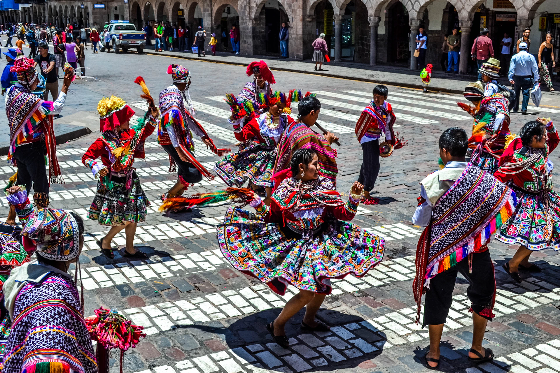 A vibrant group of dancers in colorful traditional Senegalese attire moving energetically during an outdoor cultural festival.