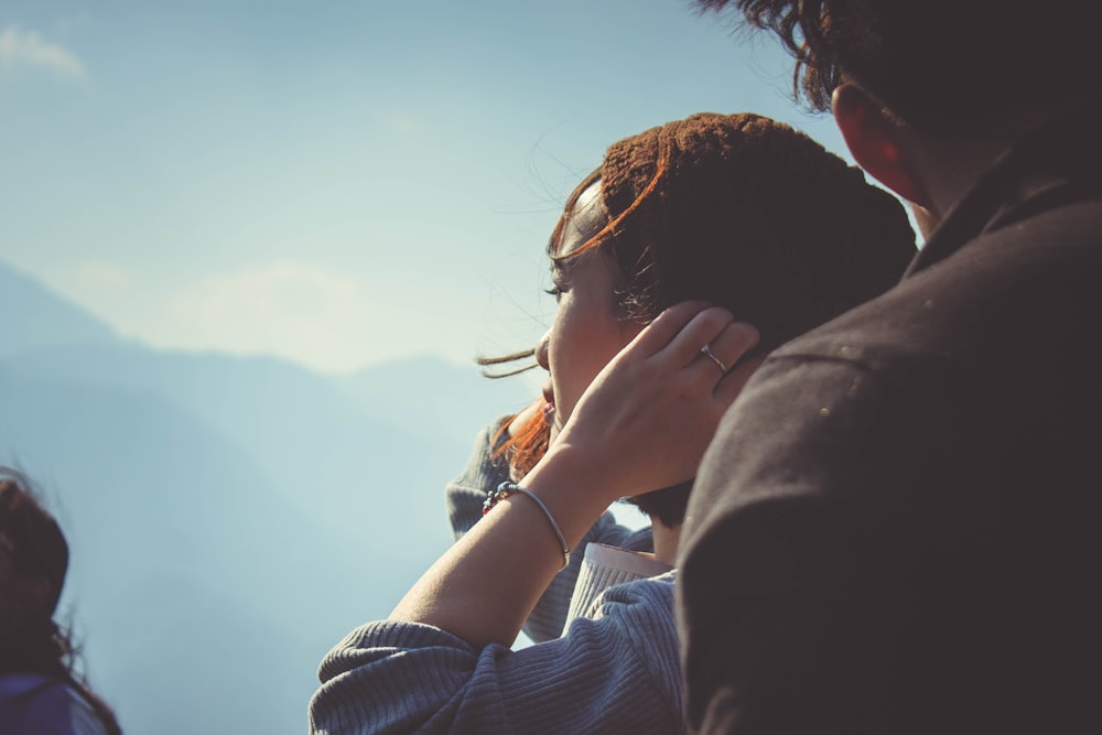 woman beside man holding her hair at daytime