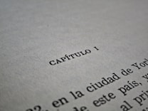 A close-up of a text document with the word 'CAP&Iacute;TULO I' centered in bold black letters on a white page. The lower part of the image shows additional text lines, partially visible and fading out of focus.