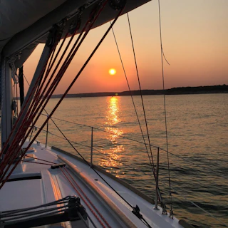 Sunset view from a yacht’s deck with golden light reflecting off calm tropical waters.