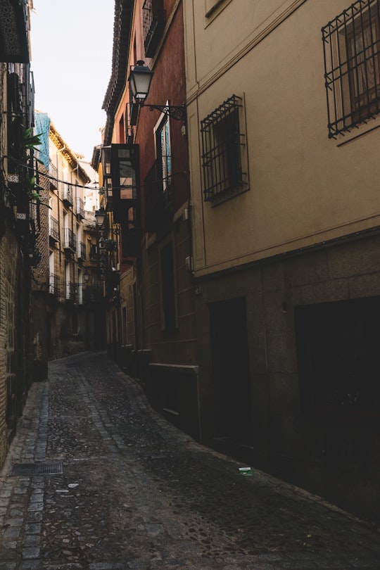 empty street in between of concrete buildings during daytime in Toledo Spain