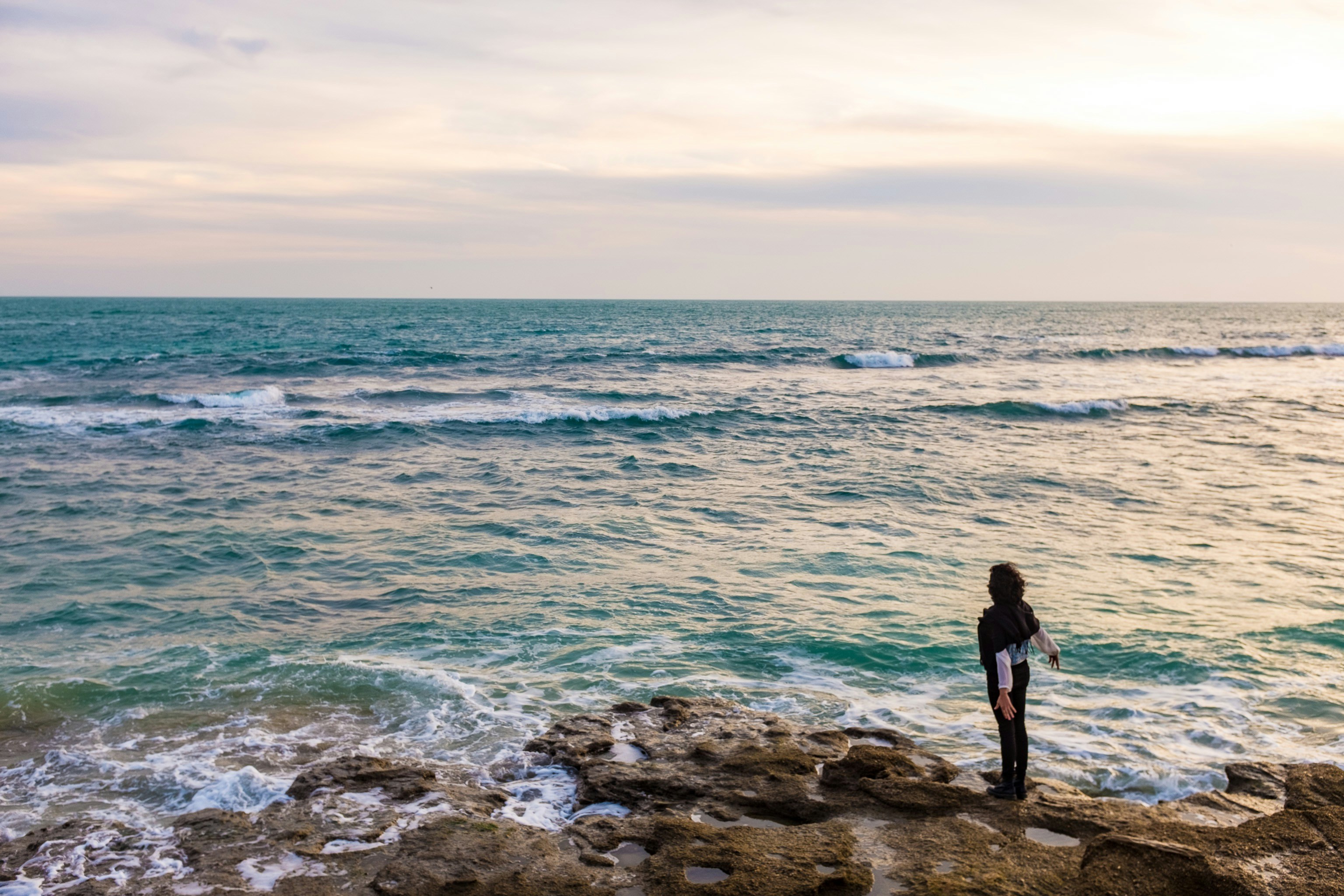 man in black shirt standing on rocky shore during daytime