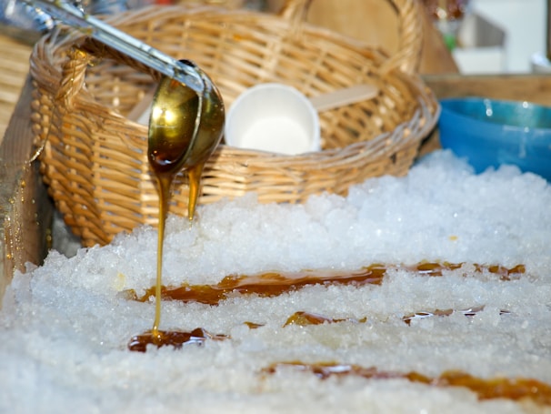 Close-up of rich, dark kithul syrup being poured over a bowl of tropical fruits.