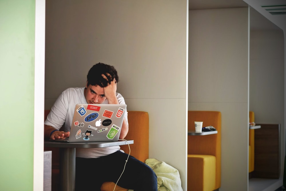 homme portant un haut blanc à l’aide d’un MacBook