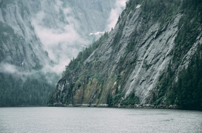 grey rock cliff near body of water alaska teams background