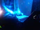 A DJ performing live in a neon-lit club with blue and violet lights.