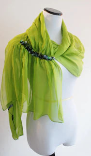 A vibrant green scarf draped elegantly over a wooden chair in natural light
