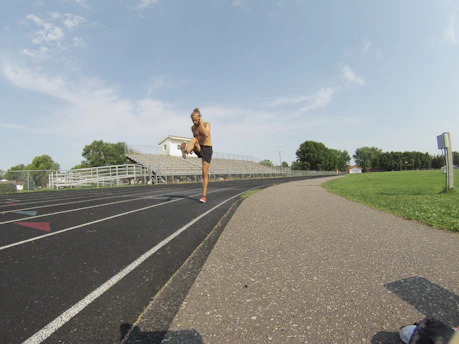 A group of athletes warming up on a track under a clear blue sky.