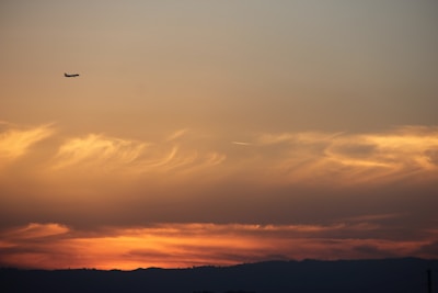 A sleek airplane soaring above clouds with a vibrant sunset backdrop, representing smooth flight bookings.