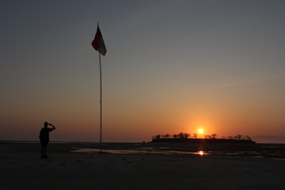 A silhouette of a soldier saluting the flag at dusk.