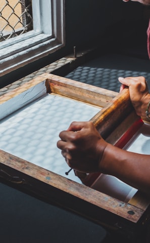 man holding printing screen near white window