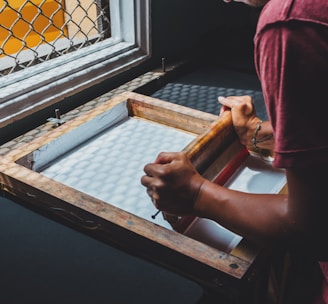 man holding printing screen near white window