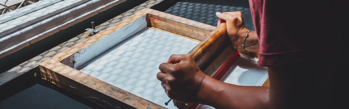 man holding printing screen near white window