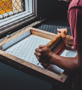 man holding printing screen near white window