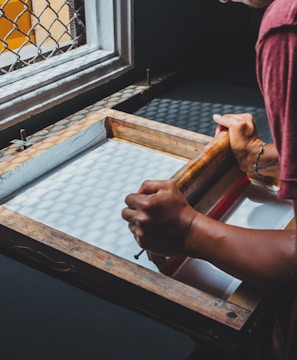 man holding printing screen near white window