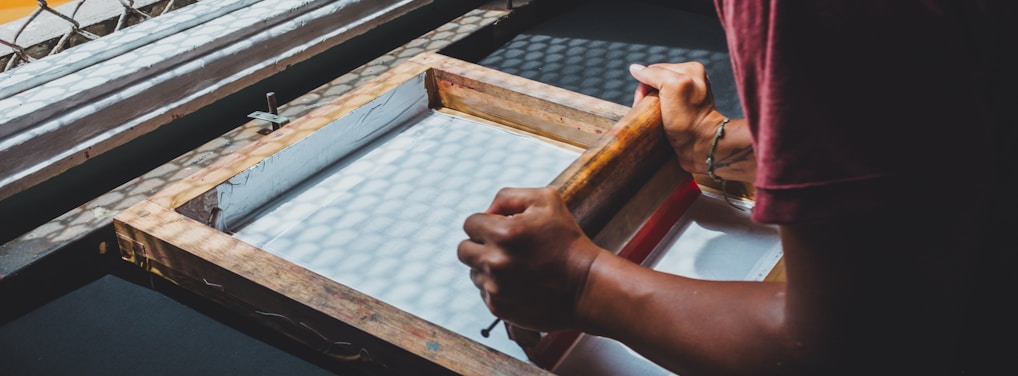 man holding printing screen near white window