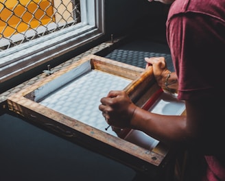 man holding printing screen near white window