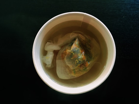 A close-up of freshly brewed black tea in a rustic cup with tea leaves scattered nearby.