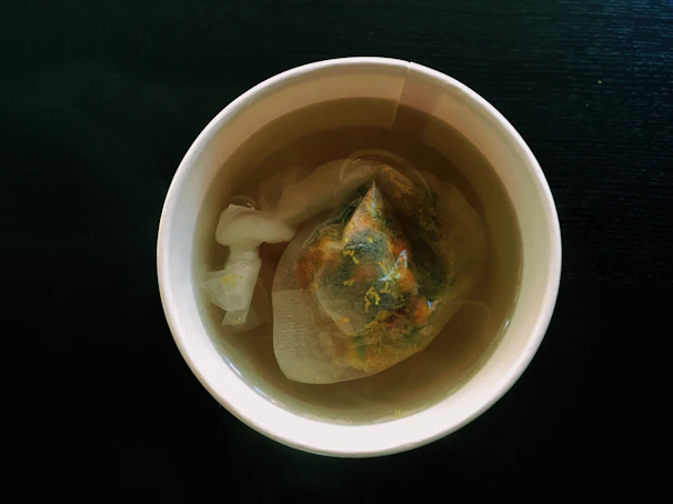 Close-up of a steaming cup of herbal tea surrounded by fresh ayurvedic herbs and spices.