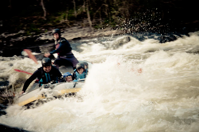 A group of friends navigating thrilling white-water rapids with bright helmets and life jackets.