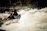 A group of adventurers navigating white-water rapids on a bright sunny day.