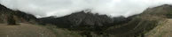 Panoramic view of the Andean mountains wrapped in thick mist with patches of cloud forest.