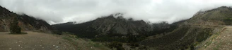 Panoramic view of the Andean mountains wrapped in thick mist with patches of cloud forest.