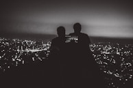 Travelers capturing a panoramic cityscape from a high viewpoint in Dubai at dusk.