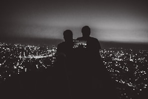 A golden hour view of a city skyline from a rooftop bar with people taking selfies