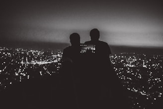 A golden hour view of a city skyline from a rooftop bar with people taking selfies