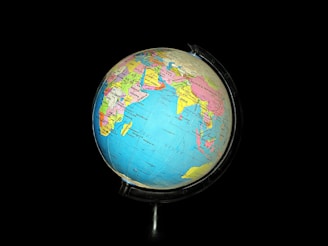 A colorful globe with detailed geographic labels, showing parts of Asia, Africa, and the Indian Ocean, set against a black background. The globe features country names and borders vividly marked in various colors.