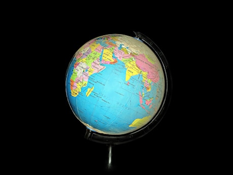 A colorful globe with detailed geographic labels, showing parts of Asia, Africa, and the Indian Ocean, set against a black background. The globe features country names and borders vividly marked in various colors.