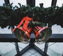 two red steel bells beside green Christmas decoration