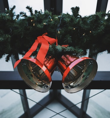 two red steel bells beside green Christmas decoration