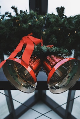 two red steel bells beside green Christmas decoration